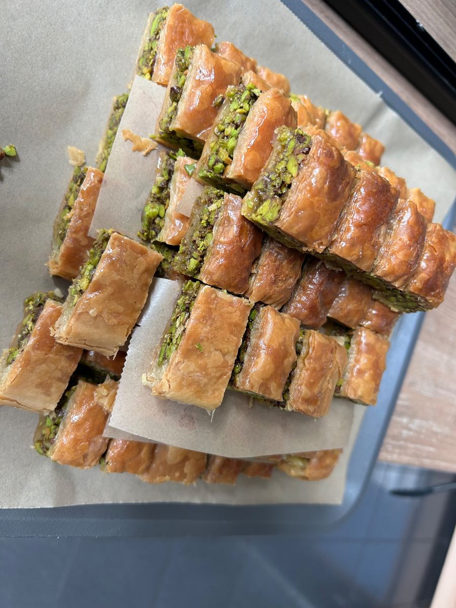 Gestapelte Baklava-Röllchen mit Pistazienfüllung auf einem Blech