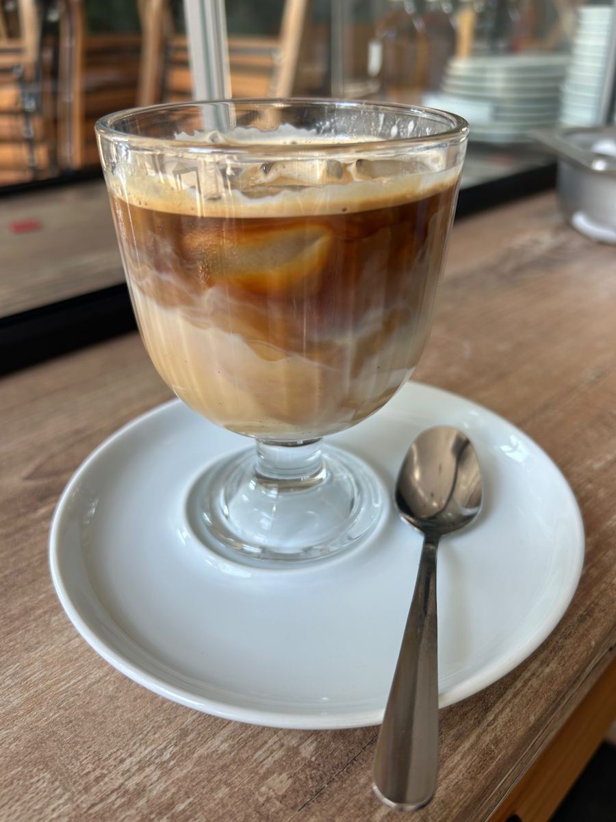 Eis-Latte im Stielglas auf einer weißen Untertasse